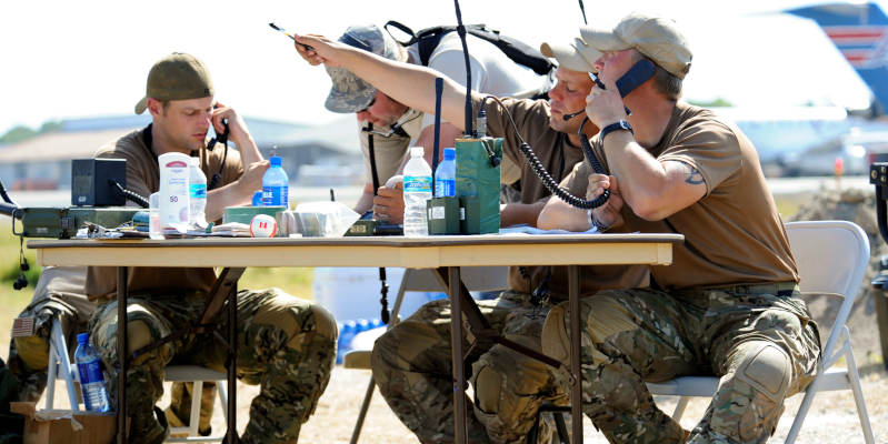 Combat controllers from 23rd Special Tactics Squadron, sit at a folding table and direct air traffic into Haiti's damaged Port Au Prince International Airport.