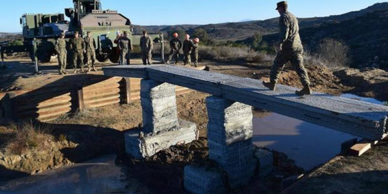 US marines walk over their concrete 3D printed bridge