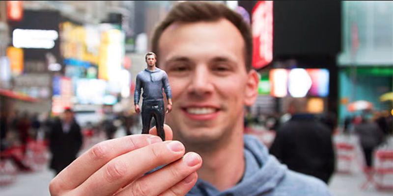 A man holding a small 3D printed figurine of himself